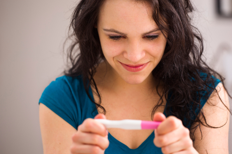 Woman looking at a positive pregnancy test